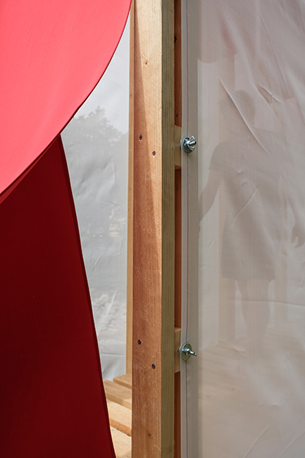 Detalle de los materiales de construcción del proyecto Landgate: la tela blanca de construcción, el tejido rojo Marzotto y la madera
